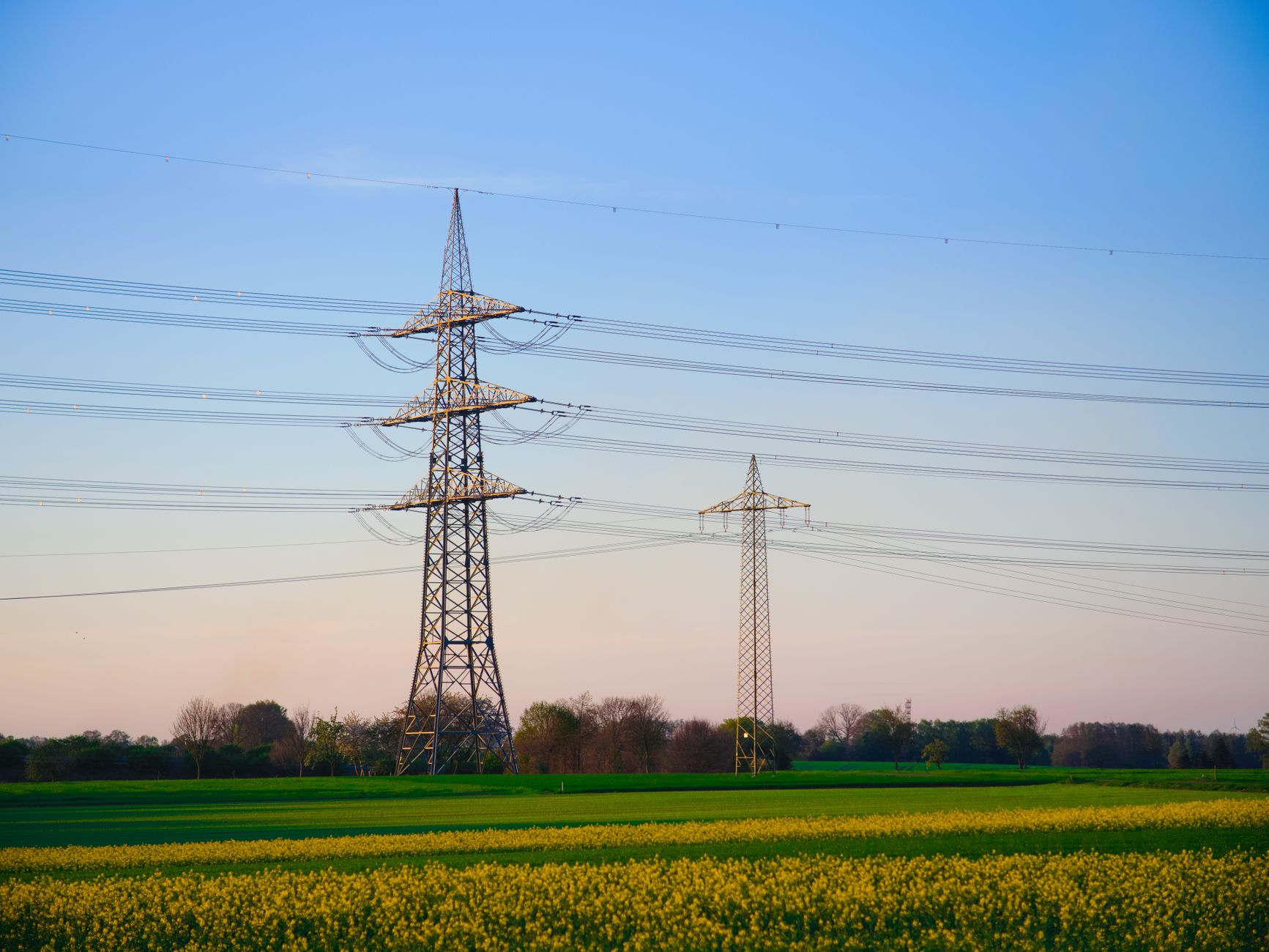 Why Transmission Is Becoming the Biggest Bottleneck in the Energy Transition — high voltage transmission lines at sunset rural landscape
