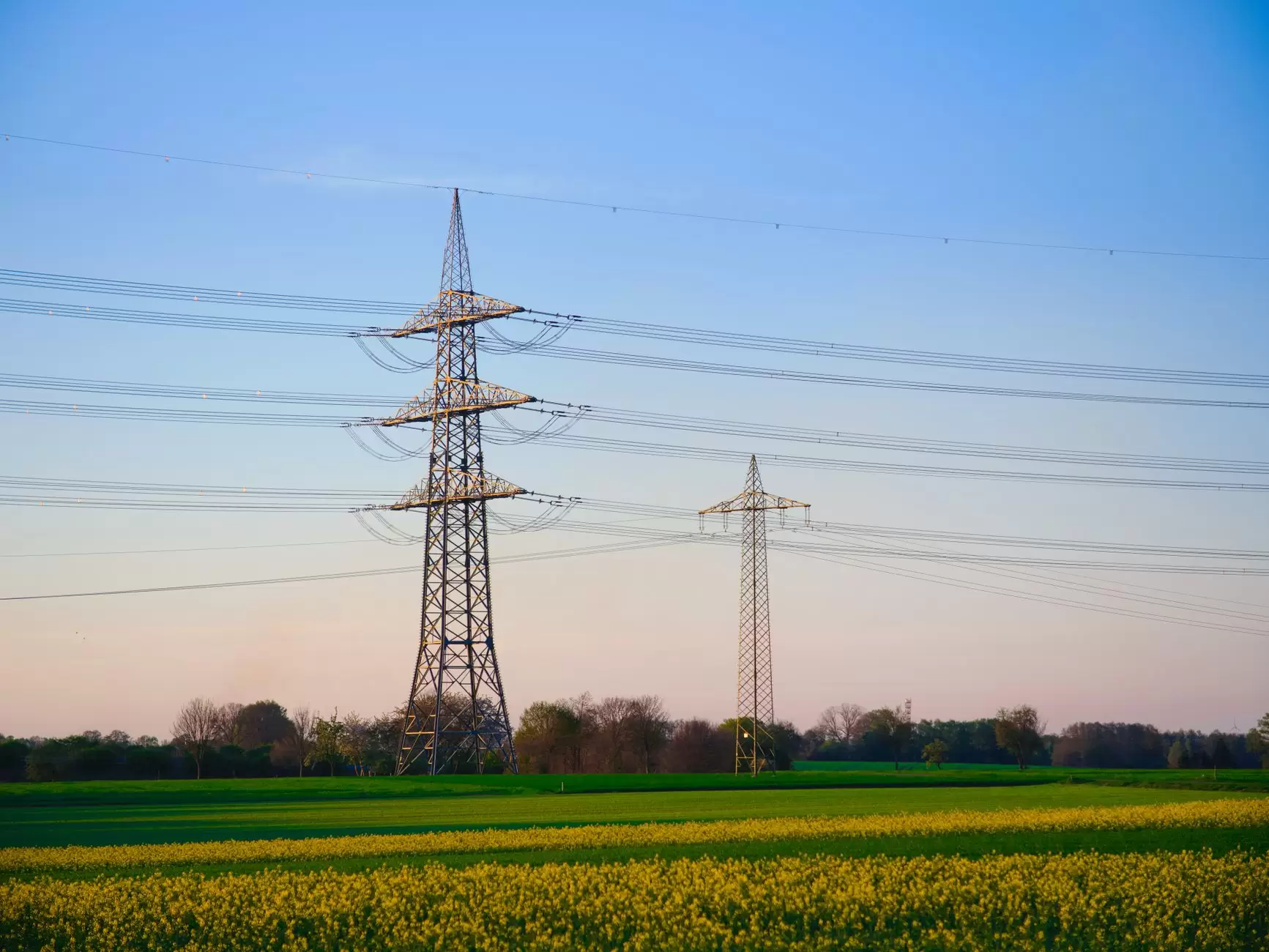 Why Transmission Is Becoming the Biggest Bottleneck in the Energy Transition — high voltage transmission lines at sunset rural landscape