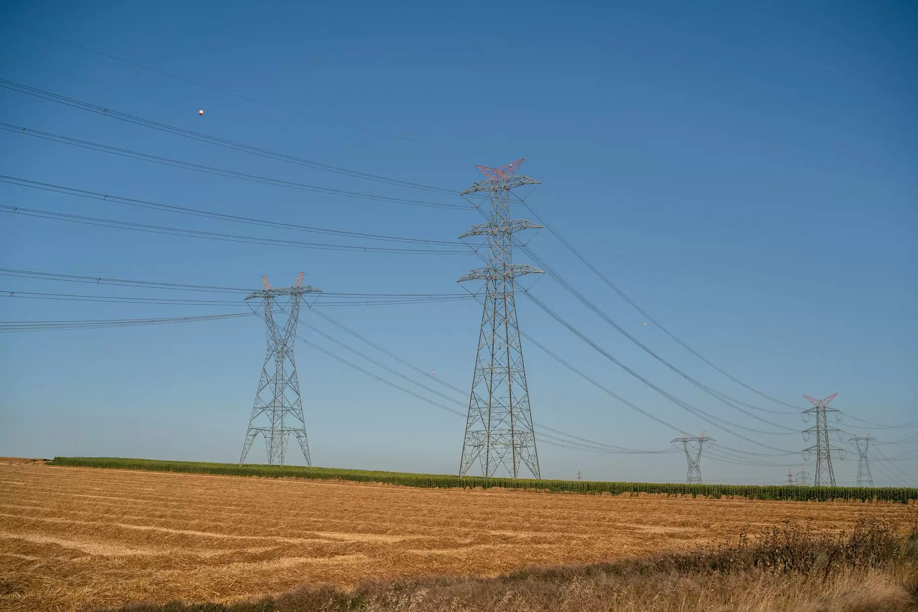 Transmission Permitting: The Institutional Maze Across Multiple Jurisdictions — high-voltage transmission towers crossing rural farmland near a state border
