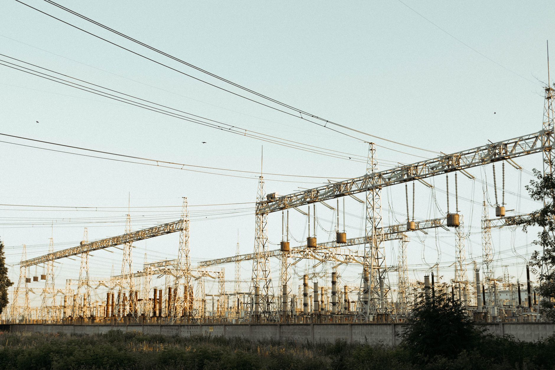 Inside the Digital Substation: How Protection and Control Are Changing — high-voltage electrical substation with transmission towers and control buildings under a clear sky