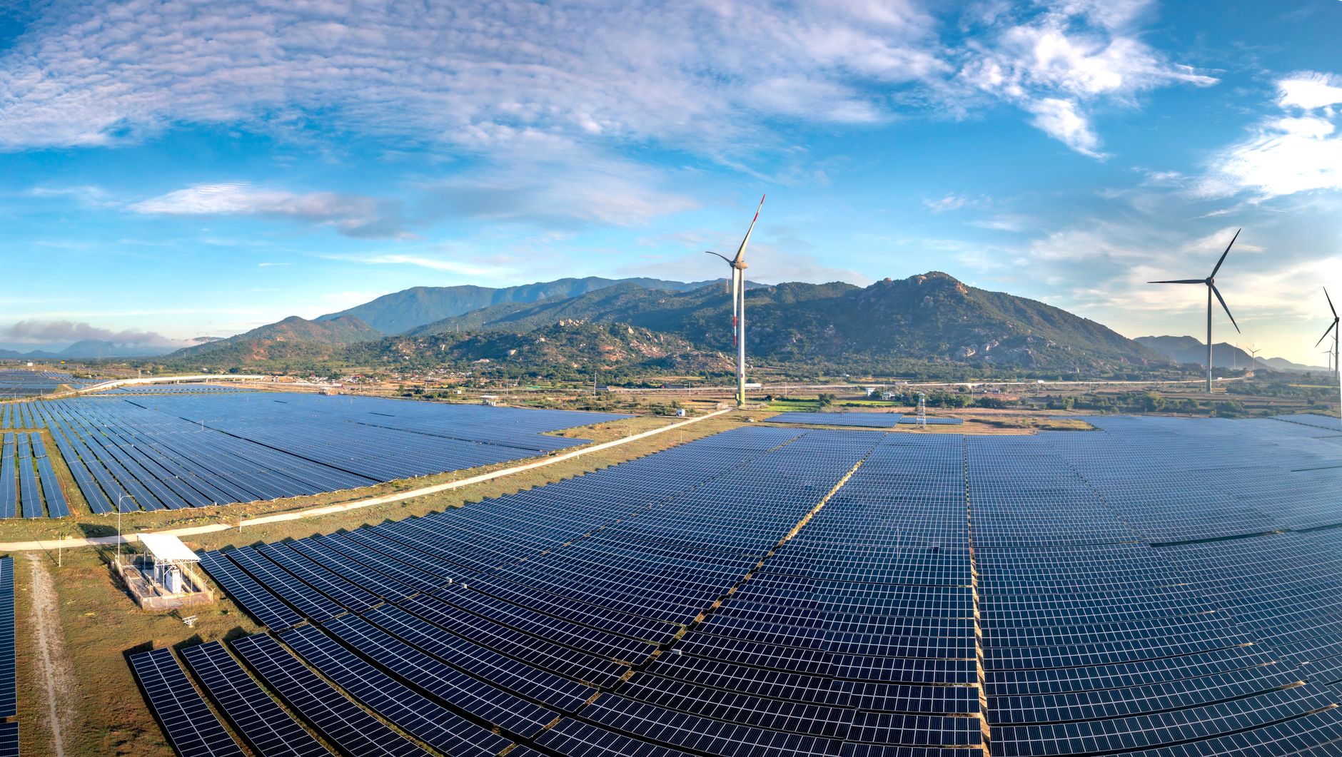 Merchant Risk and the Rise of Corporate PPAs in Renewable Finance — utility-scale wind turbines and solar panels across an open landscape with power lines