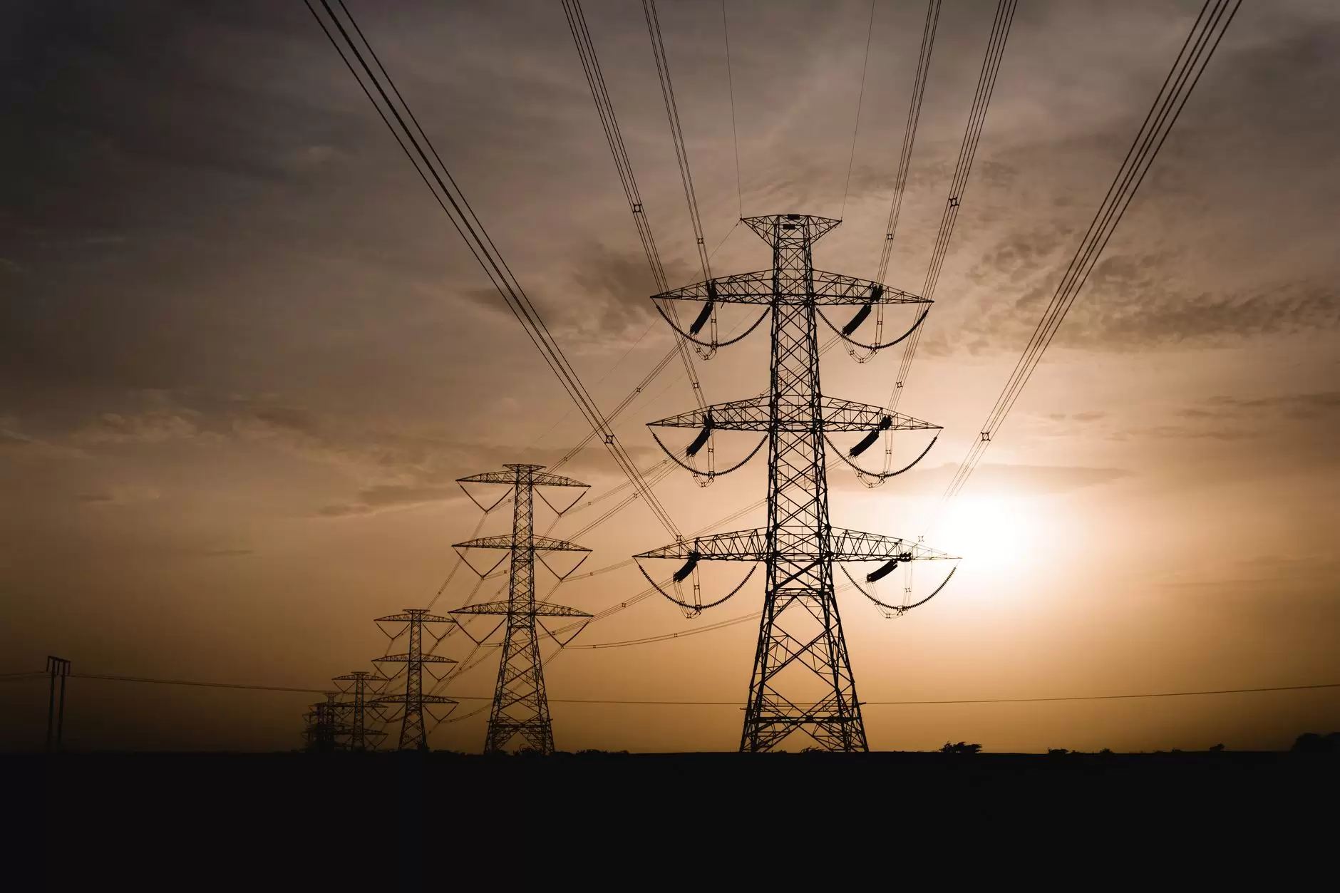 How Grid-Scale Batteries Make Money: The Markets from Regulation to Black Start — utility-scale battery storage containers beside high-voltage transmission lines at sunset