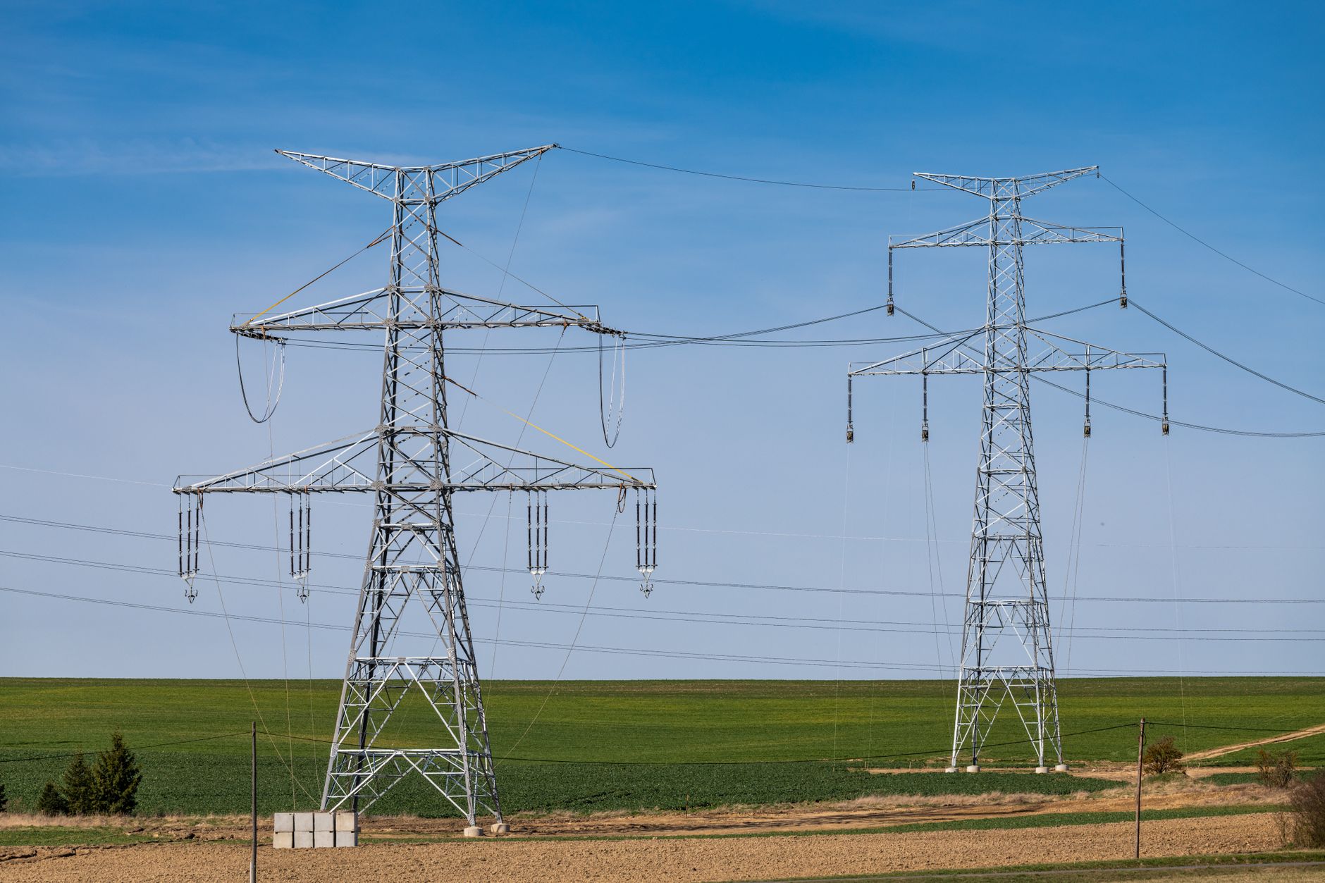 What Causes Grid Congestion: Physical Limits and Market Signals — high-voltage transmission lines crossing a wide landscape on a hot clear afternoon