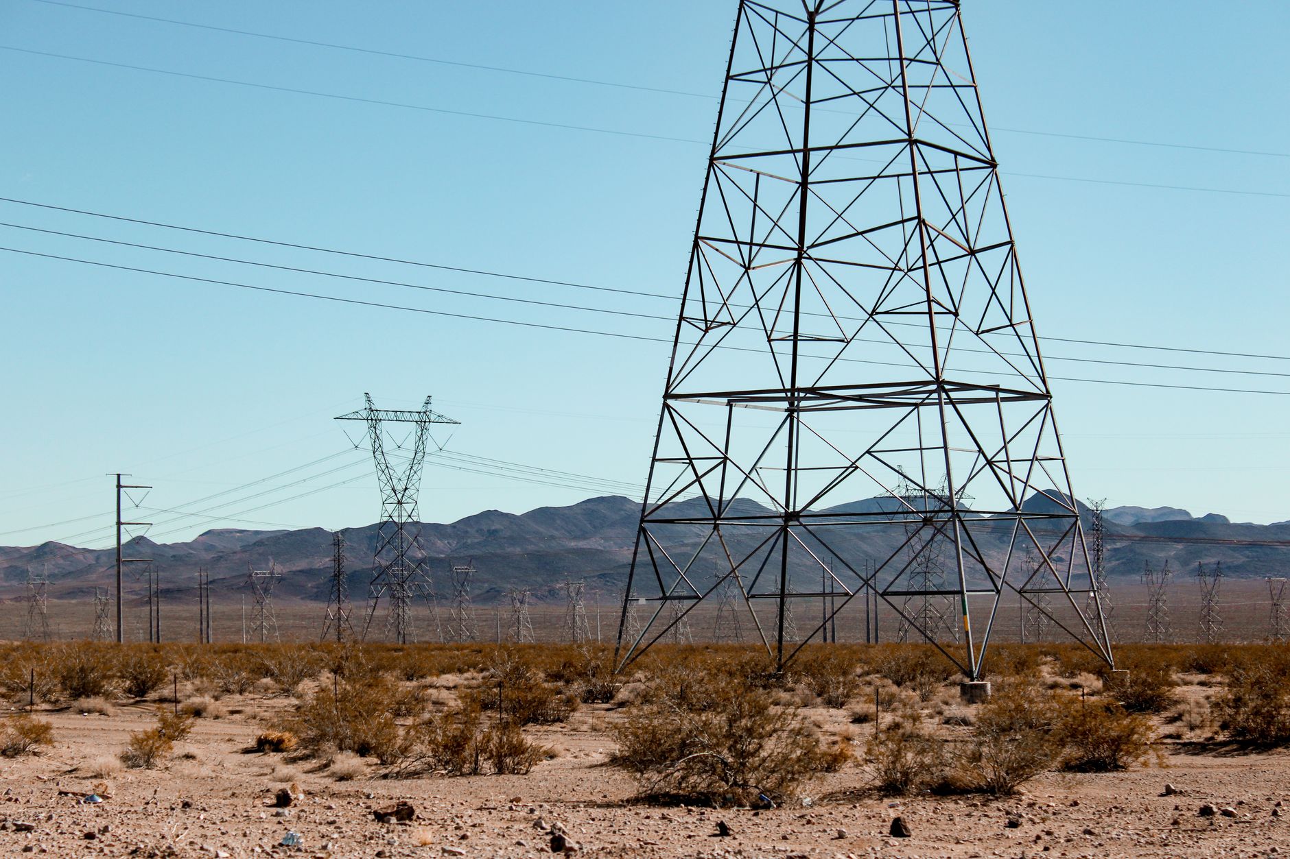 India's Electricity Sector: Why Growth Outpaces the Grid — high-voltage transmission towers crossing a dry Indian landscape under a hazy sky