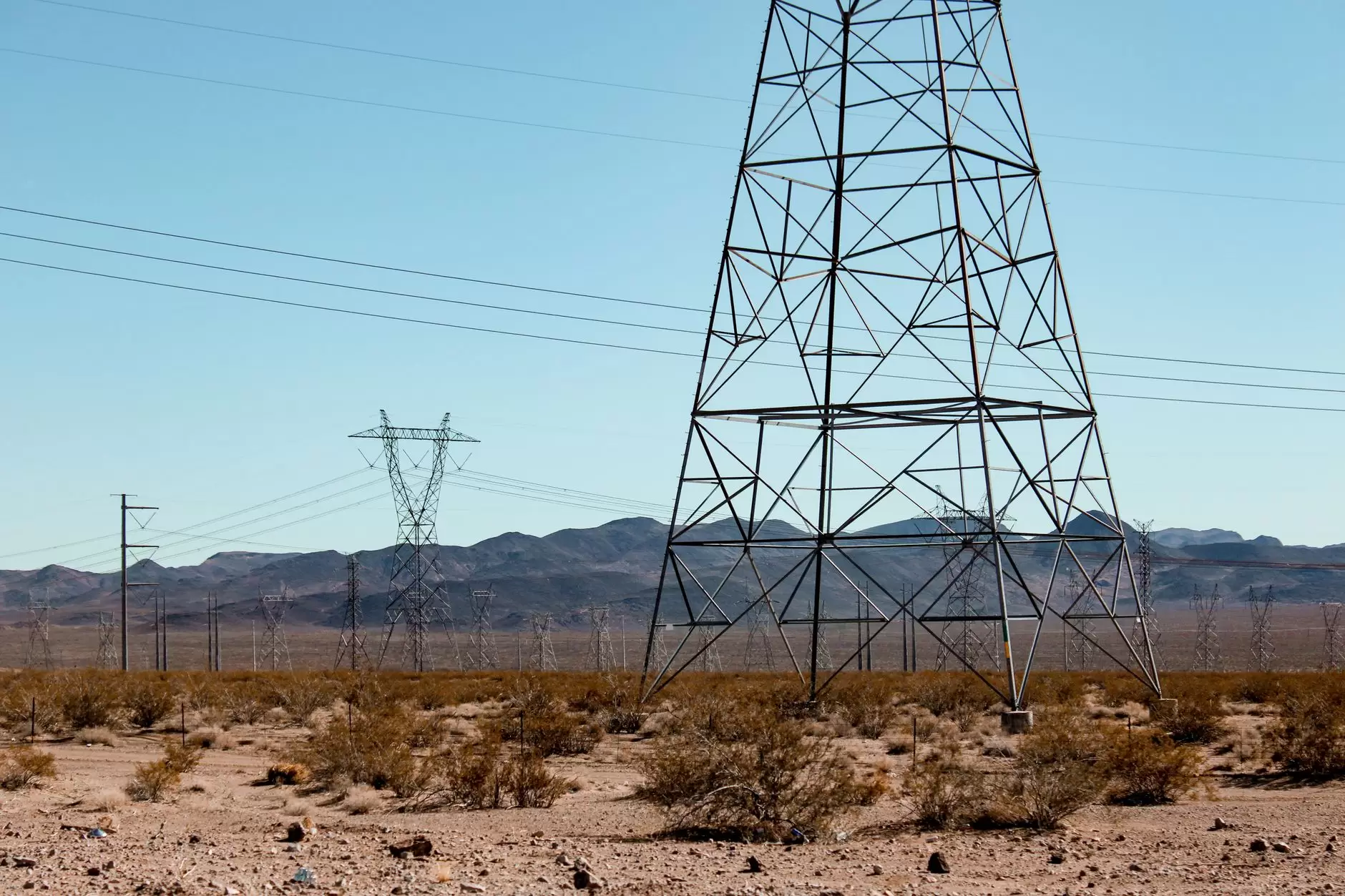India's Electricity Sector: Why Growth Outpaces the Grid — high-voltage transmission towers crossing a dry Indian landscape under a hazy sky
