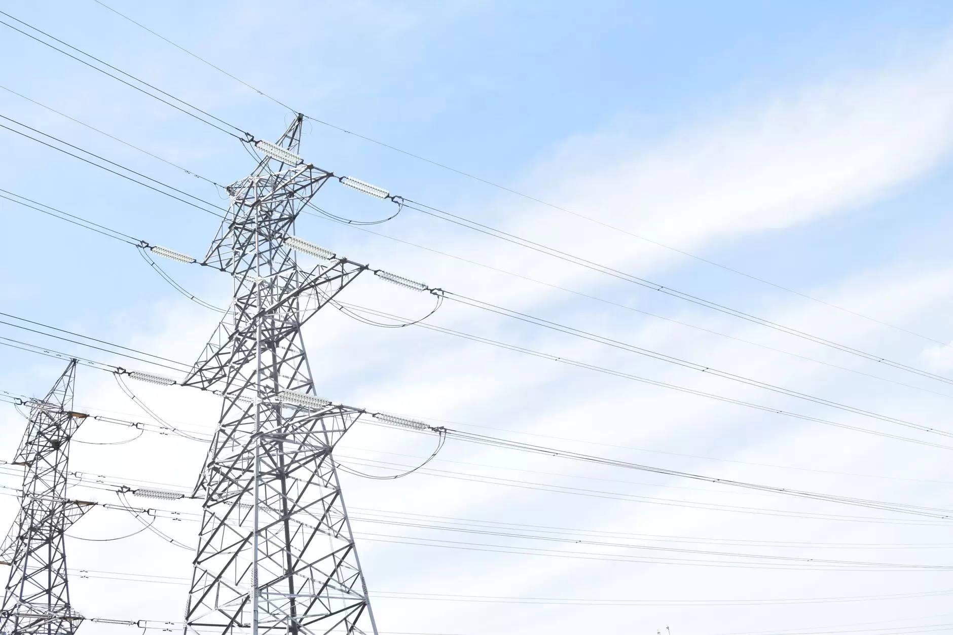 Peaker Plants in a Battery-Rich Grid: The Economics of the Last 5% — natural gas peaker plant turbines and exhaust stacks beside high-voltage transmission lines at dusk