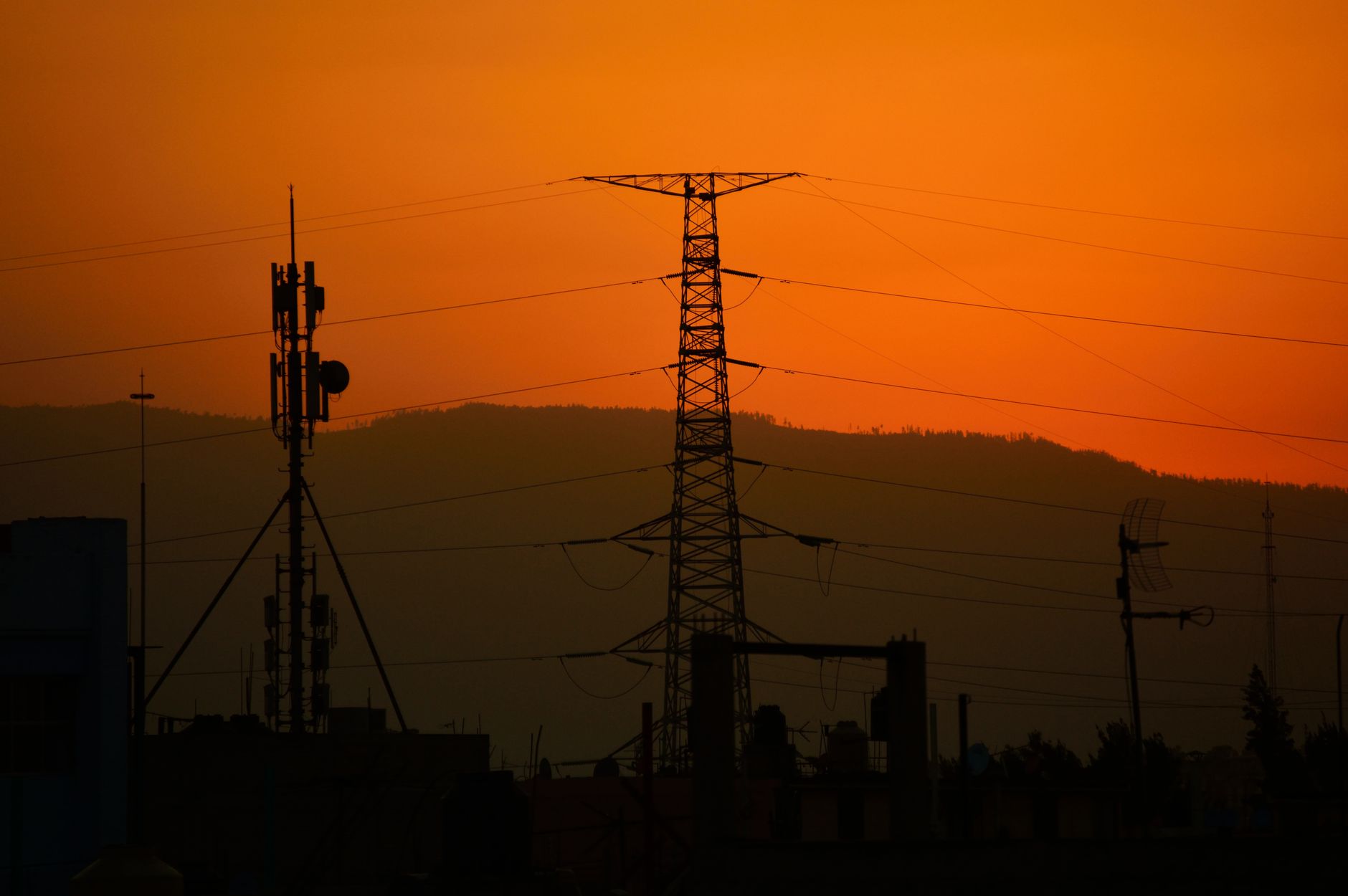 The Economic and Reliability Case for Connecting Southeast Asia's Electricity Systems — high-voltage transmission lines crossing tropical mountain landscape at sunset