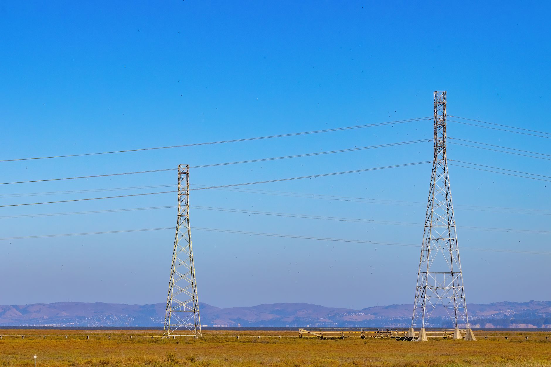 The Lao PDR–Thailand–Malaysia–Singapore Power Integration Project: Regional Trade’s Pathfinder — high-voltage transmission towers crossing a tropical landscape with distant mountains