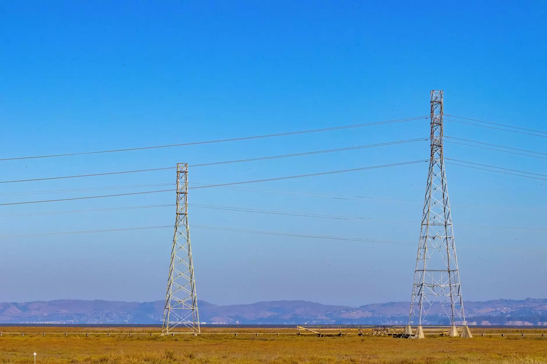 The Lao PDR–Thailand–Malaysia–Singapore Power Integration Project: Regional Trade’s Pathfinder — high-voltage transmission towers crossing a tropical landscape with distant mountains