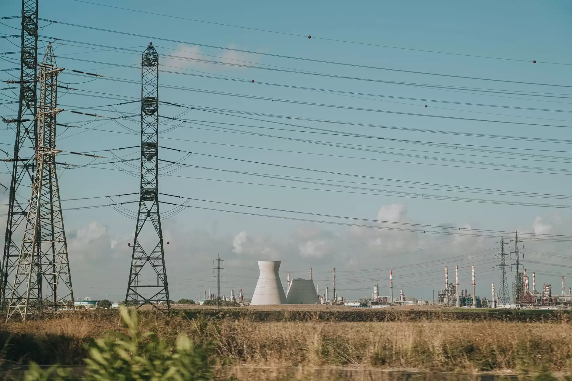China's Power Market Reforms: What the Provincial Spot Pilots Show — high voltage transmission towers crossing a broad Chinese industrial landscape under cloudy skies