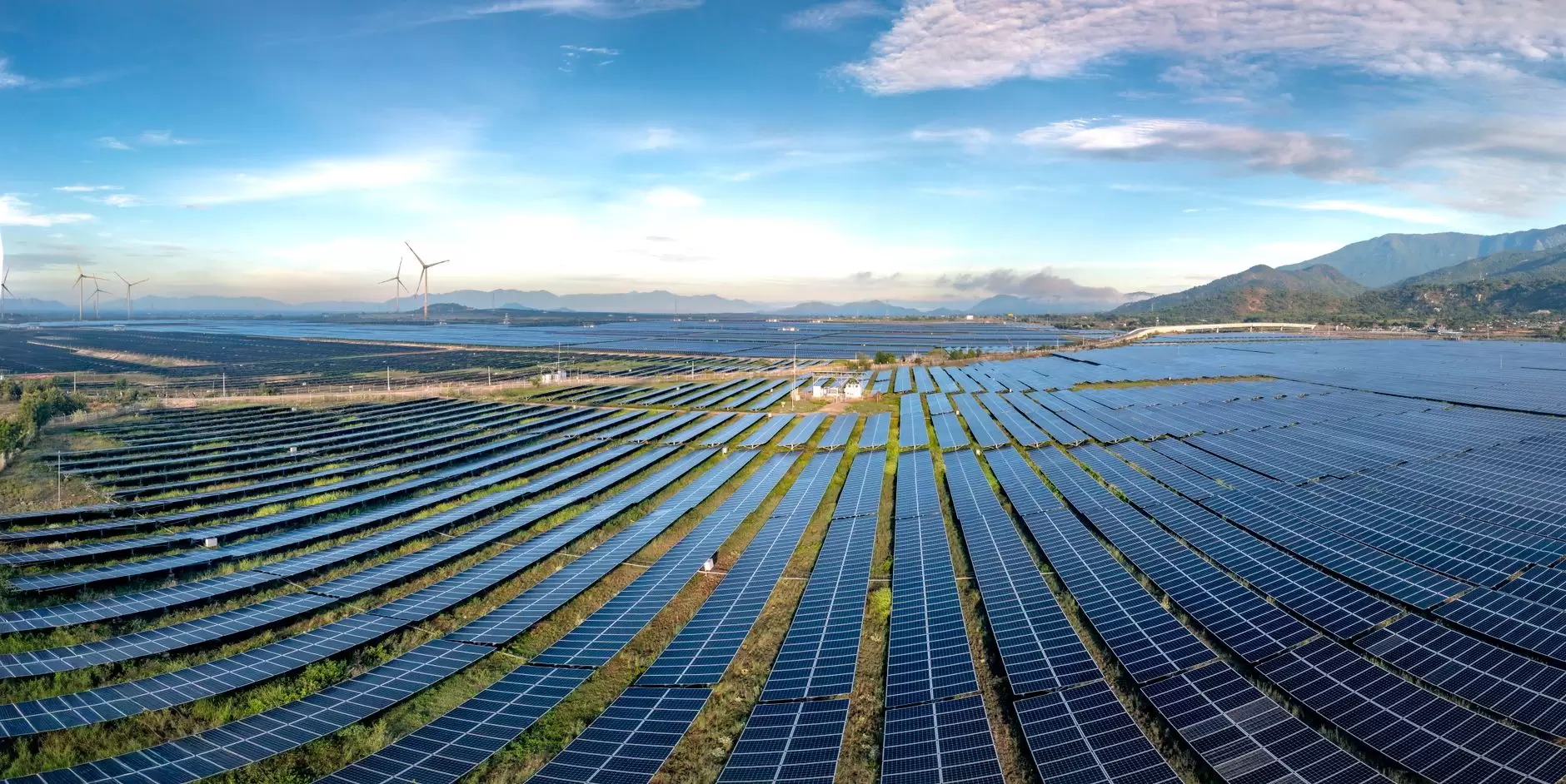 Why Co-Locating Solar and Storage Changes the Economics of a Project — utility-scale solar farm with containerized battery storage across a wide field