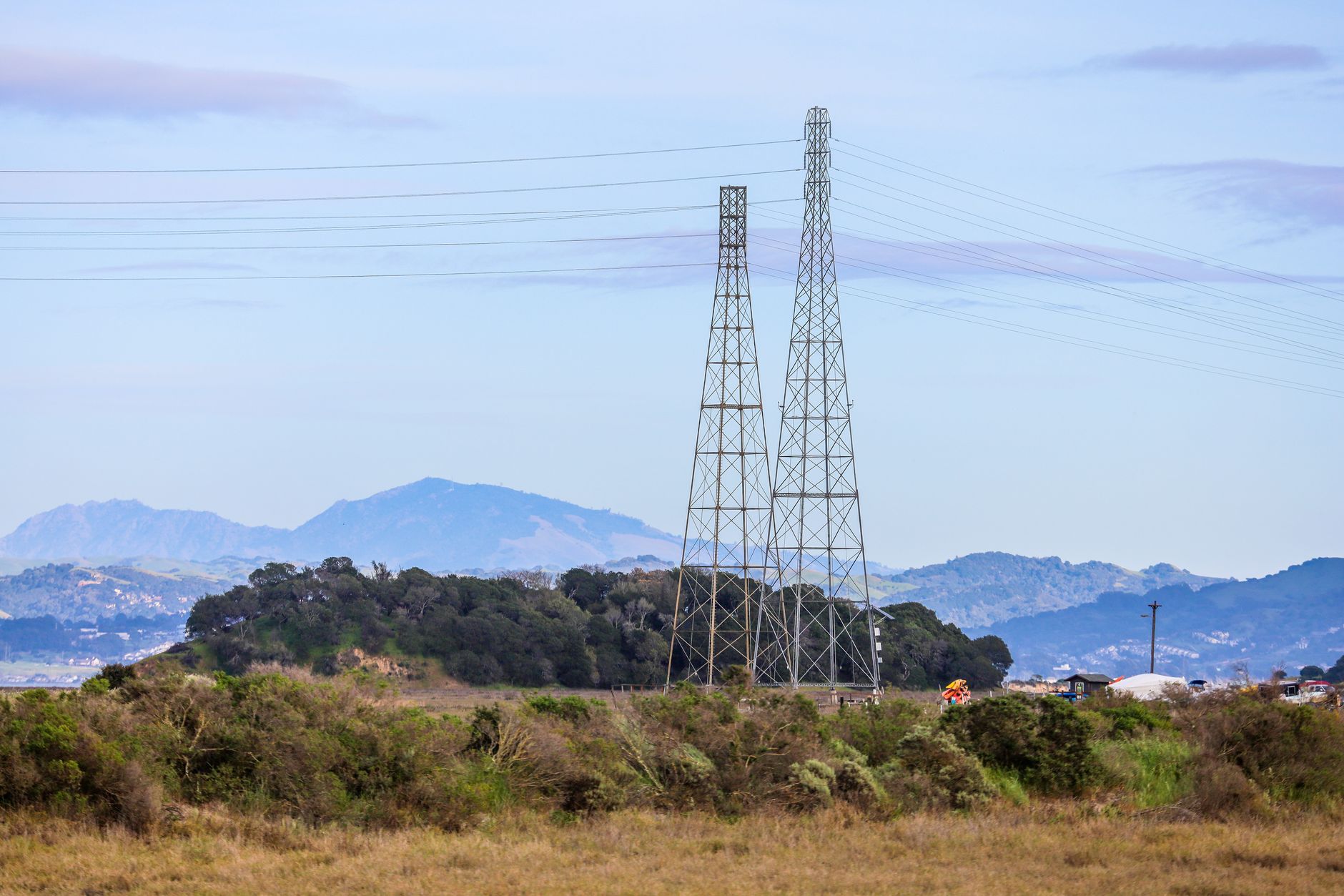 India to Singapore: What a 2 GW Power Corridor Requires — high-voltage transmission towers crossing tropical hills and rural landscape