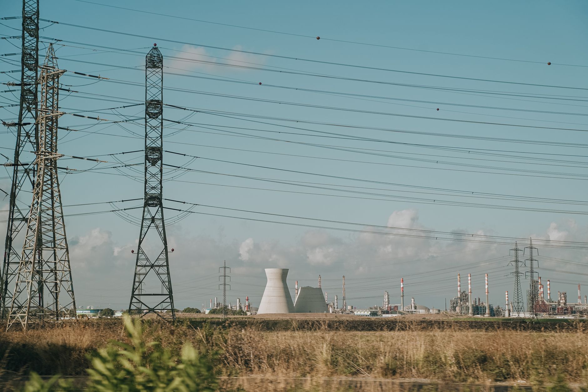 Malaysia's Power Sector: Gas, Independent Power Producers, and the Net-Zero Transition — natural gas power plant with cooling towers and transmission lines under a cloudy sky